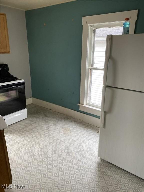 kitchen with freestanding refrigerator, baseboards, and gas stove