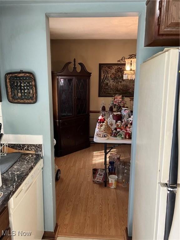 interior space featuring light wood-type flooring, white appliances, and dark countertops