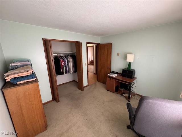 bedroom with a closet, light carpet, a textured ceiling, and baseboards