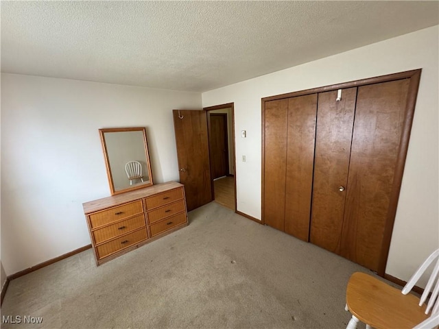 bedroom featuring a textured ceiling, a closet, and light colored carpet