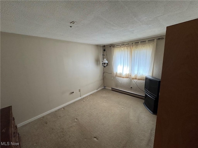 carpeted spare room featuring baseboards, baseboard heating, and a textured ceiling