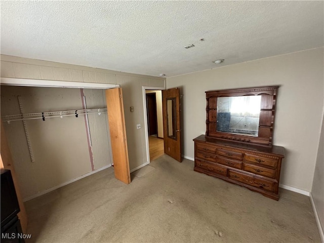 unfurnished bedroom with carpet, a textured ceiling, baseboards, and a closet