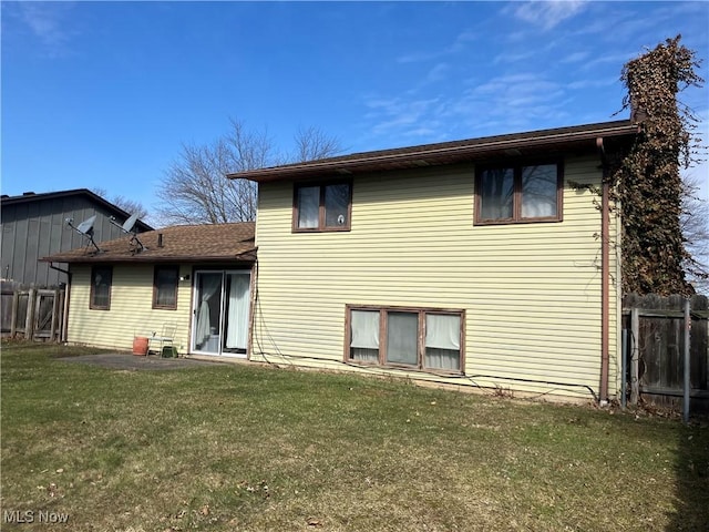 back of house featuring a lawn and fence