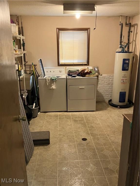 clothes washing area with independent washer and dryer, laundry area, and electric water heater