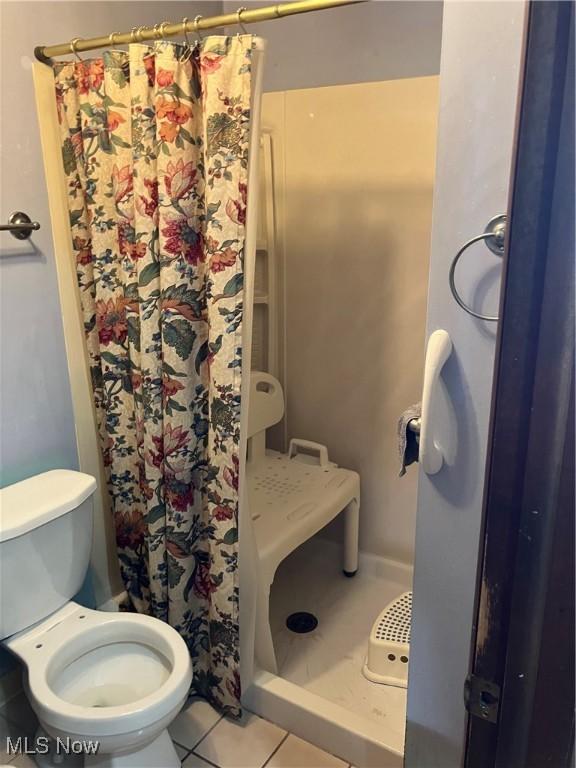 full bathroom with a shower with shower curtain, toilet, and tile patterned floors