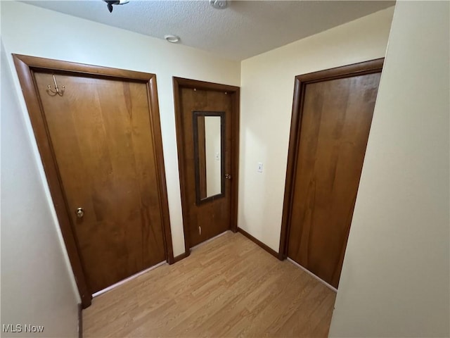 unfurnished bedroom featuring light wood-style flooring, baseboards, and a textured ceiling