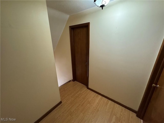 interior space featuring light wood-style flooring, baseboards, and a textured ceiling