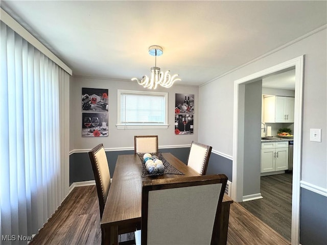 dining space featuring dark wood-type flooring, a notable chandelier, and baseboards