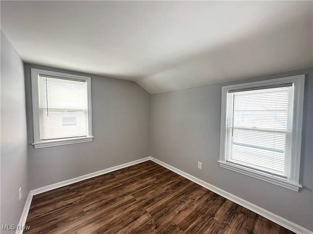 bonus room featuring dark wood finished floors, vaulted ceiling, plenty of natural light, and baseboards