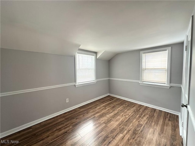 bonus room featuring lofted ceiling, dark wood finished floors, and baseboards