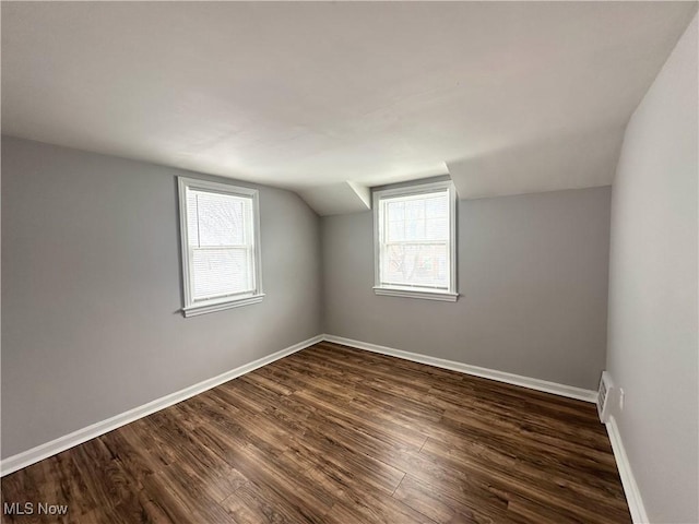 bonus room with dark wood finished floors, a wealth of natural light, and baseboards