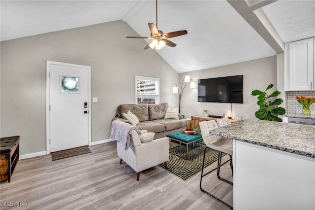 living room with lofted ceiling, light wood-type flooring, a ceiling fan, and baseboards