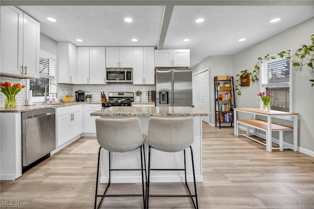 kitchen with light wood finished floors, plenty of natural light, stainless steel appliances, and a sink