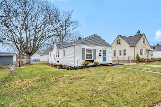 view of front facade with entry steps, a chimney, fence, and a front yard