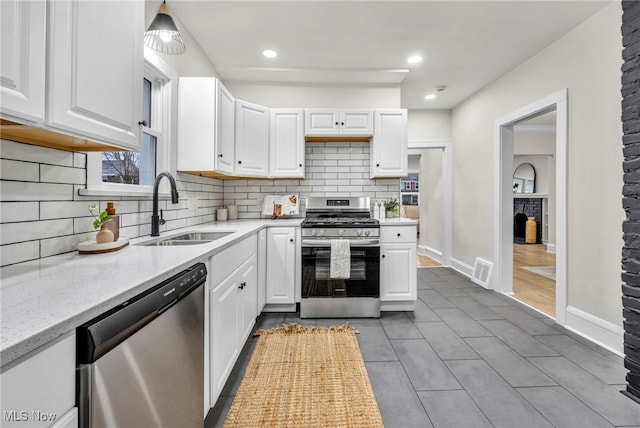 kitchen featuring light stone counters, visible vents, appliances with stainless steel finishes, white cabinets, and a sink