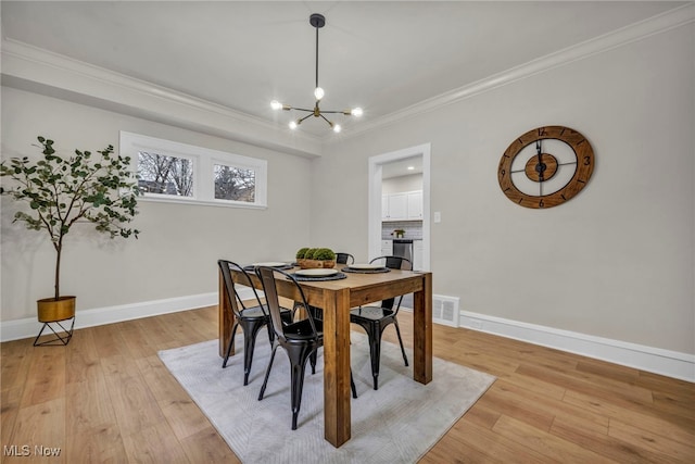 dining area featuring an inviting chandelier, light wood-style flooring, baseboards, and crown molding