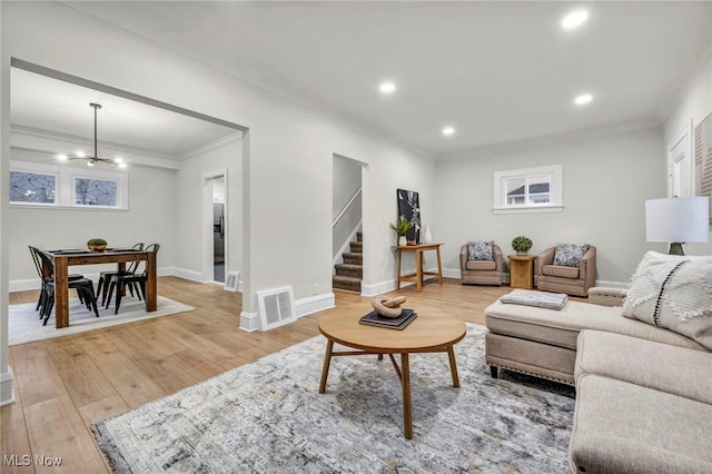 living area featuring crown molding, visible vents, stairway, light wood-type flooring, and baseboards