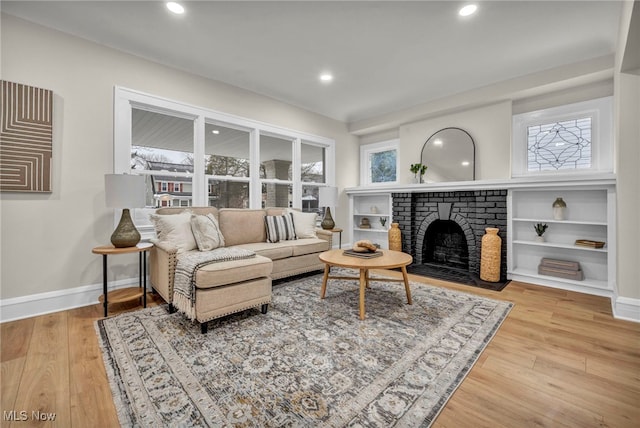 living area featuring a brick fireplace, baseboards, wood finished floors, and recessed lighting