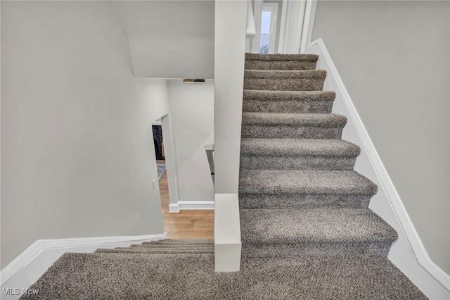 staircase featuring baseboards and wood finished floors