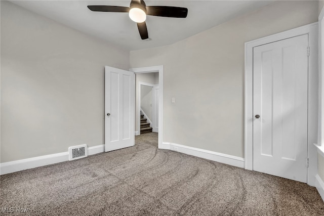 unfurnished bedroom with carpet floors, a ceiling fan, visible vents, and baseboards