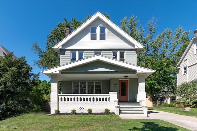 traditional style home with a chimney, a front lawn, and a porch