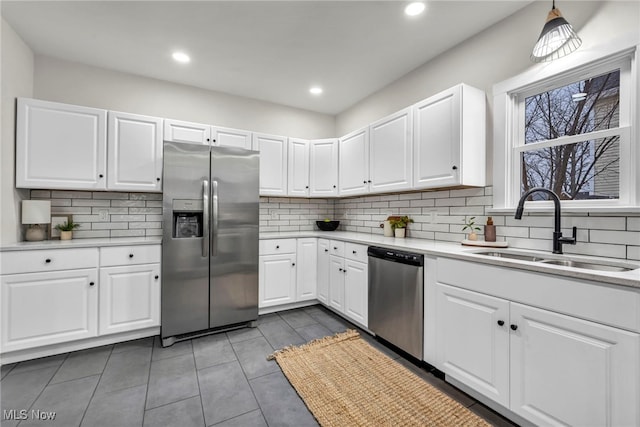 kitchen featuring appliances with stainless steel finishes, white cabinets, light countertops, and a sink