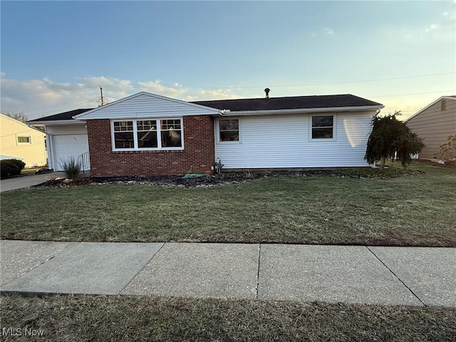 view of front facade with a garage, driveway, a front lawn, and brick siding