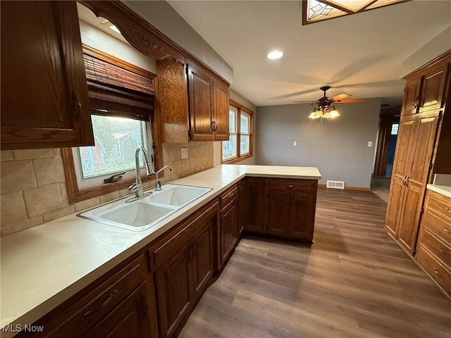 kitchen featuring a peninsula, wood finished floors, a sink, visible vents, and light countertops