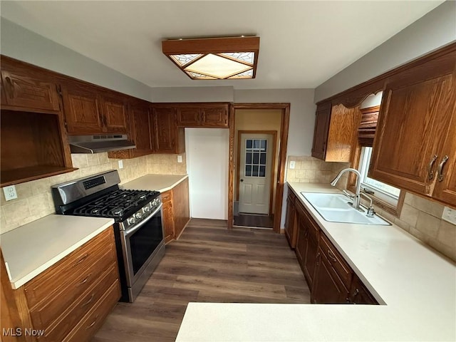 kitchen featuring gas stove, light countertops, a sink, and under cabinet range hood