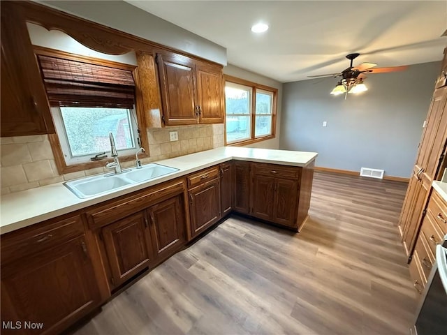 kitchen featuring a sink, visible vents, light wood-style floors, light countertops, and backsplash