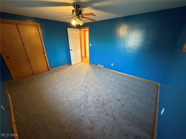 unfurnished bedroom with baseboards, visible vents, a ceiling fan, carpet floors, and a closet