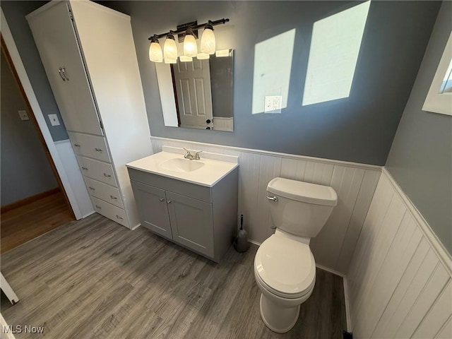 bathroom featuring a wainscoted wall, vanity, wood finished floors, and toilet