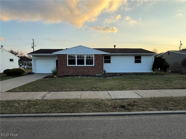 view of front of house featuring a yard, driveway, brick siding, and a garage