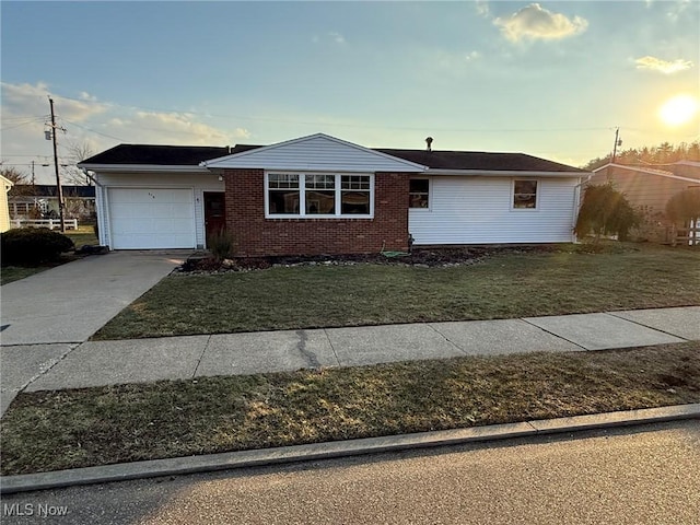 single story home with an attached garage, driveway, brick siding, and a front yard