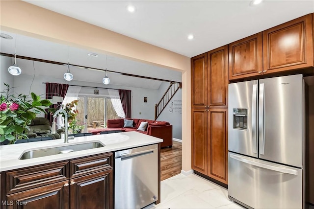 kitchen with appliances with stainless steel finishes, open floor plan, marble finish floor, light countertops, and a sink