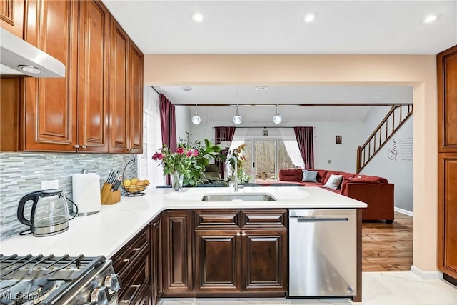 kitchen with stainless steel appliances, light countertops, a sink, a peninsula, and under cabinet range hood