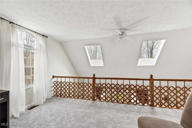 sitting room with a textured ceiling, carpet floors, vaulted ceiling with skylight, and visible vents