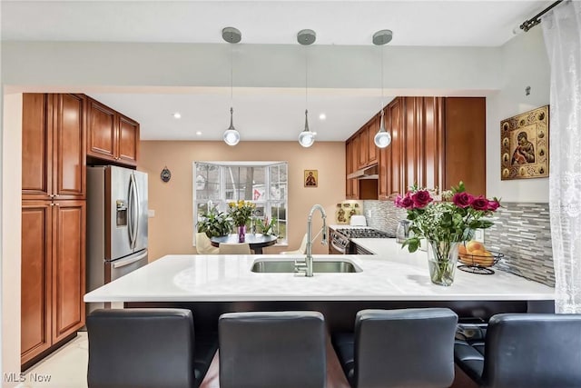 kitchen with appliances with stainless steel finishes, under cabinet range hood, light countertops, and a peninsula