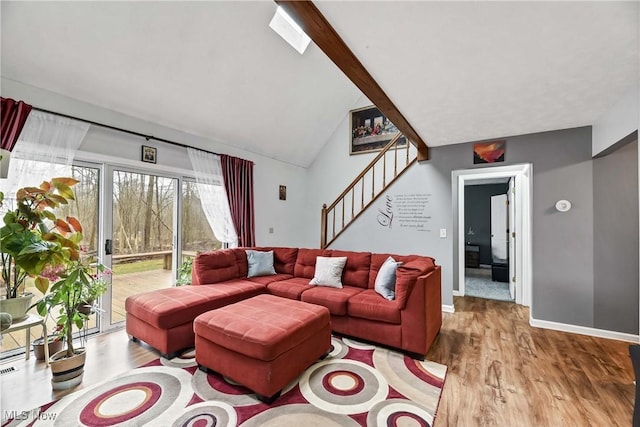 living room featuring vaulted ceiling with skylight, stairway, wood finished floors, and baseboards