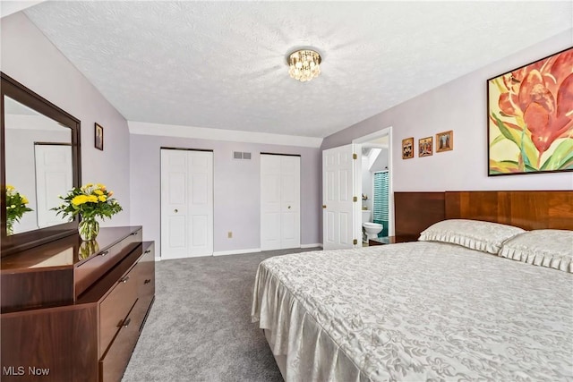 bedroom featuring carpet flooring, visible vents, a textured ceiling, and two closets