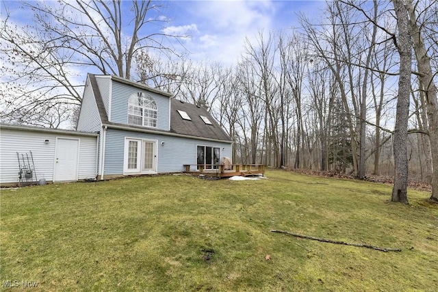 rear view of house featuring roof with shingles, a deck, and a yard