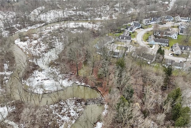 snowy aerial view featuring a water view and a residential view