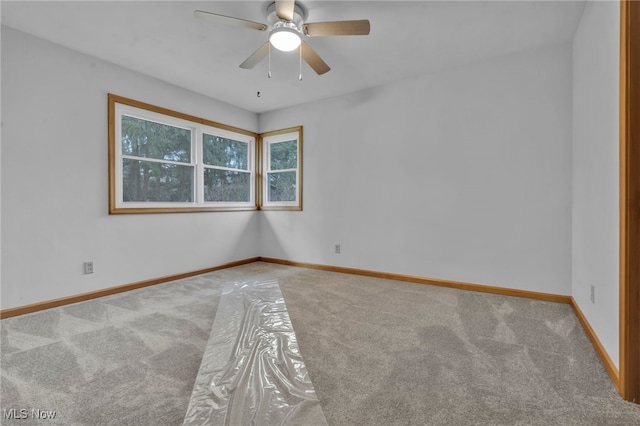 carpeted spare room with ceiling fan and baseboards