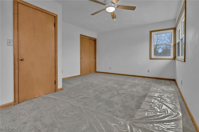 unfurnished bedroom featuring carpet, a ceiling fan, and baseboards