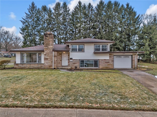 tri-level home with a garage, driveway, stone siding, a chimney, and a front yard