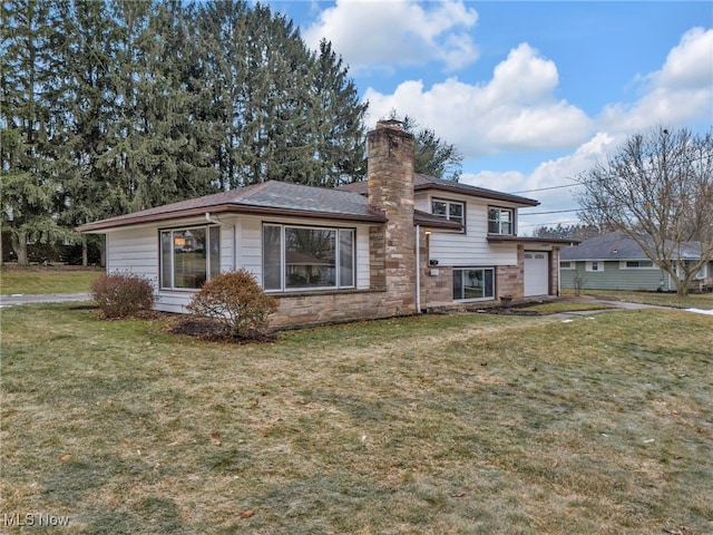 split level home with a garage, stone siding, a chimney, and a front lawn