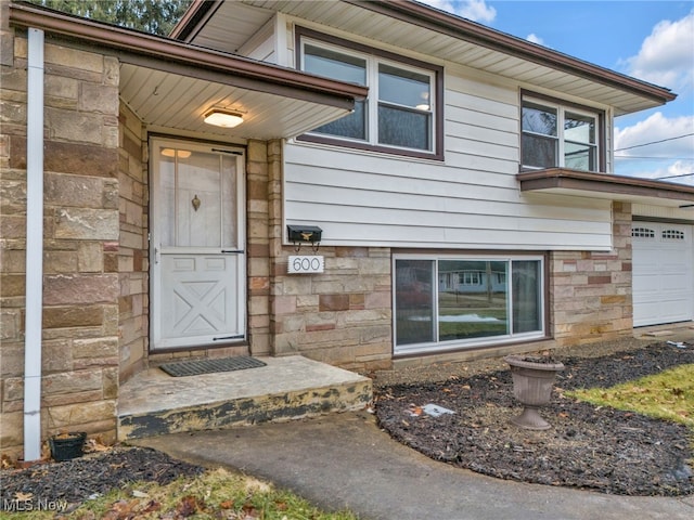 doorway to property with a garage and stone siding