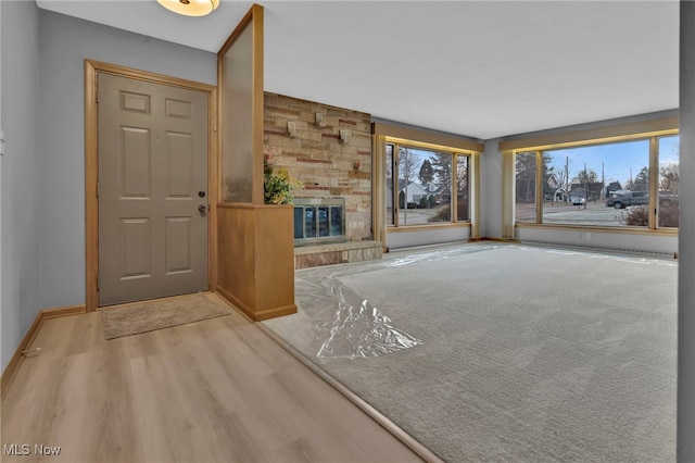 foyer with a fireplace, baseboards, and wood finished floors