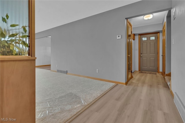 hall featuring visible vents, baseboards, and wood finished floors