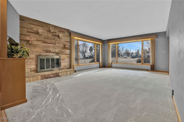 unfurnished living room featuring a healthy amount of sunlight, carpet, and a stone fireplace